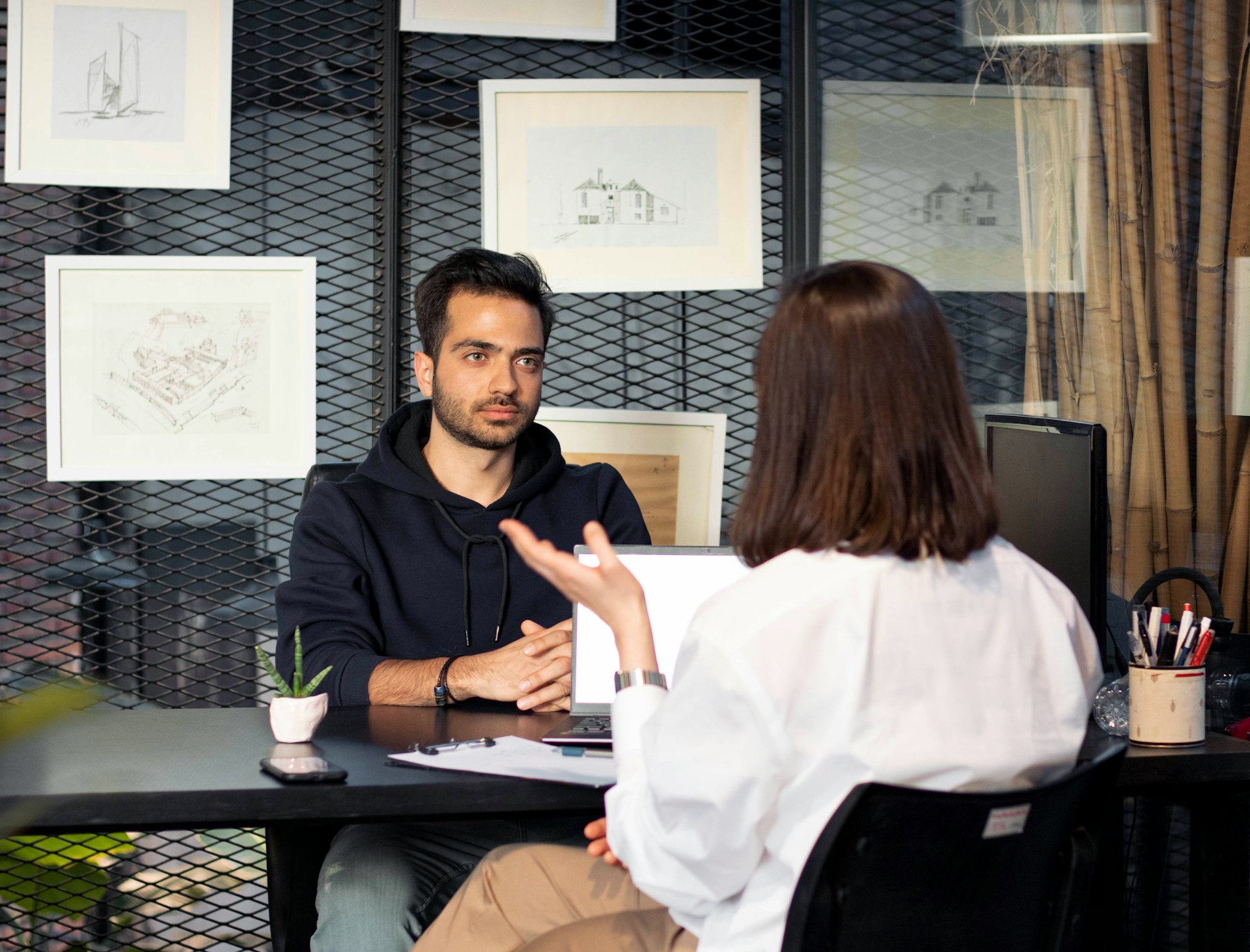 a man sitting at a desk talking to a woman